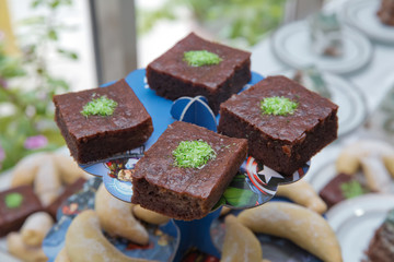 Integral Banana Cake . baked square pieces of chocolate pie with walnuts on a black board, top view . Delicious Chocolate Fudge Cake with Coconut Topping on a White Plate