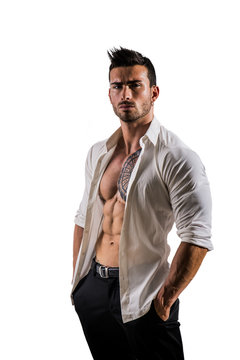 Elegant muscular attractive young man with white shirt open on naked torso, isolated against white wall