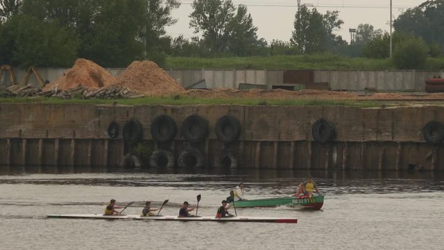Four oarsmen swim in a kayak and next to the boat sails the coach, rowing