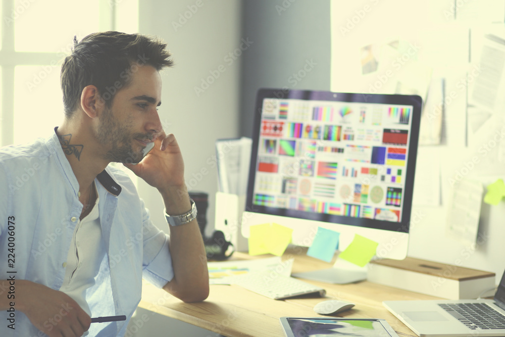 Aufkleber portrait of young designer sitting at graphic studio in front of laptop and computer while working o