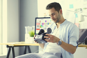 Young male software programmer testing a new app with 3d virtual reality glasses in office.