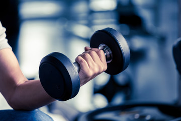 Fototapeta na wymiar Fit young man focused on lifting a dumbbell during an exercise class in a gym