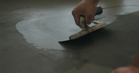 closeup worker applying micro concrete on the floor with a trowel - obrazy, fototapety, plakaty