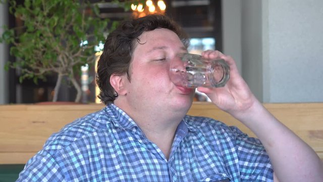 Fat man in the cafe or restaurant drinking cola