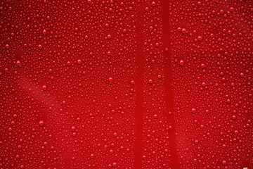Fototapeta premium Closeup rain drops on red car with hydrophobic coating