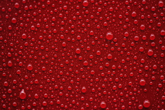 Fototapeta Closeup rain drops on red car with hydrophobic coating