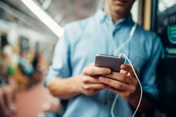 Male person using phone in subway car, addiction