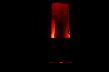 Silhouette of an unknown shadow figure on a door through a closed glass door. The silhouette of a human in front of a window at night. Scary scene halloween concept