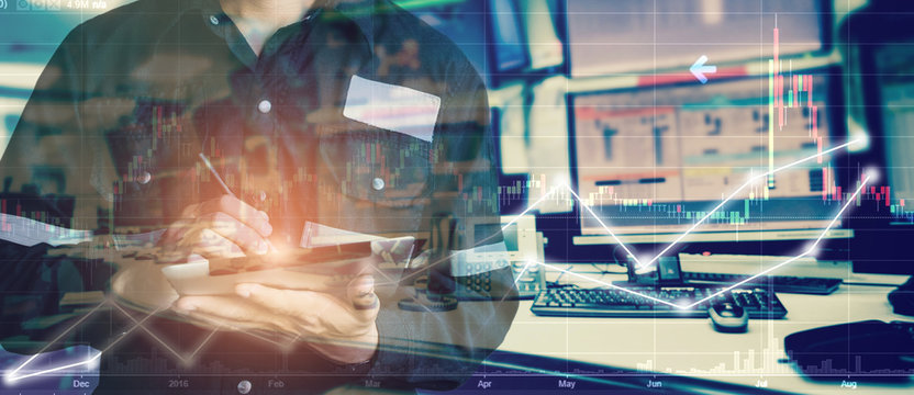 Double exposure of engineer man holding tablet for Stock market quotes and chart in monitor computer room with business office equipments .business and money trading concept