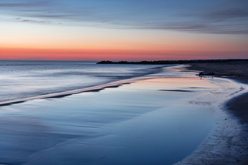 Summer night sunset beach colorful light on a danish beach at a calm evening with sky reflection on a wet sand.  Lønstrup in North Jutland in Denmark, Skagerrak, North Sea