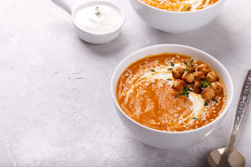 Carrot pumpkin soup with spicy chickpeas and sesame seeds on gray stone background copy space