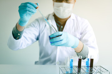 Chemist scientist conducts experiments by synthesising compounds with using dropper in a test tube.