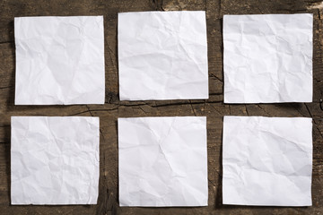 Six crumpled blank white note papers on wooden surface