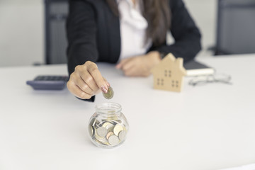 business woman saving for buy house.put coin to glass cup and calculate money.