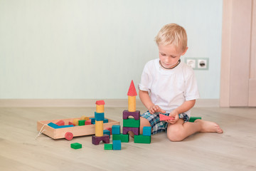 Cute little boy playing with colored wooden blocks