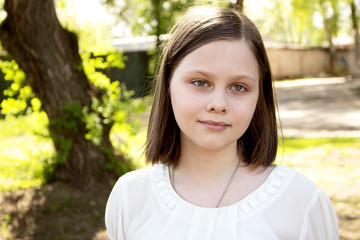Fototapeta premium Portrait of a teenage girl, in strict clothing. The girl in the park