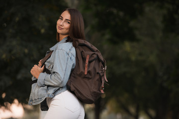 Woman in autumn season clothes with backpack at the park