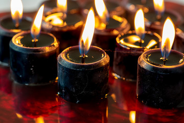 A set of twelve black candles lit sitting on a large pool of blood. Perfect scary background for Halloween.
