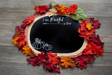 A autumn, fall inspired I am thankful for background surrounded by fall leaves on a wooden table. Perfect for a Thanksgiving message.