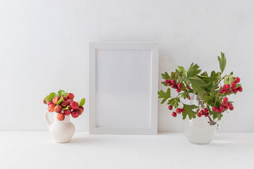 Mockup white frame and branches with red berries in a vase