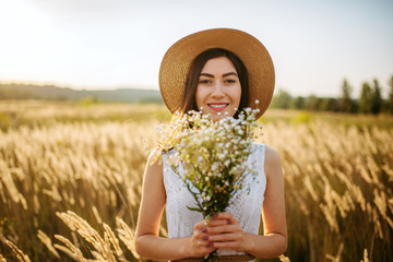Woman with bouquet of wild flowers in a rye field