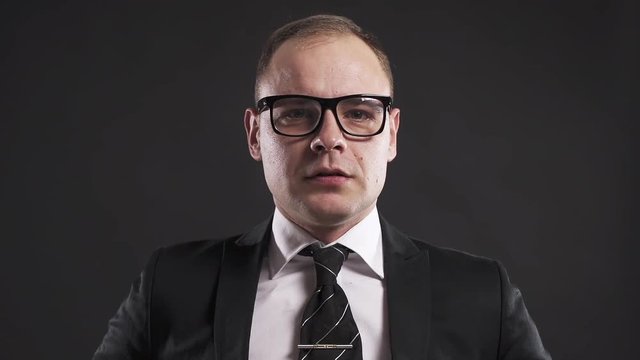 Severe businessman caucasian man boss in suit and glasses chastises you on gray background pov, isolated portrait