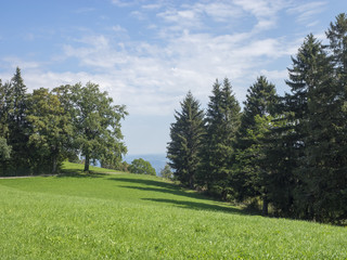 Fototapeta na wymiar Paysages de Bavière. Vues sur les collines, prairies verdoyantes et pâturages autour du village de Hundham dans la vallée du Leitzach au pied du Schwarzenberg.