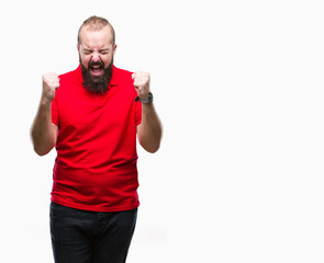 Fototapeta premium Young caucasian hipster man wearing red shirt over isolated background excited for success with arms raised celebrating victory smiling. Winner concept.