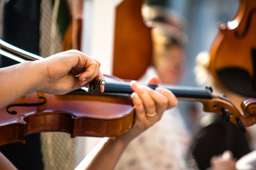A young girl is playing a violin. Street, sunny day. Close-up.