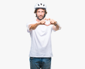 Handsome hispanic cyclist man wearing safety helmet over isolated background smiling in love showing heart symbol and shape with hands. Romantic concept.