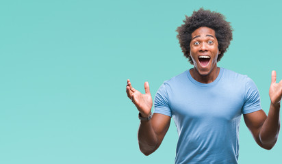 Afro american man over isolated background celebrating crazy and amazed for success with arms...