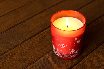 Burning Christmas candle on wooden table. Christmas and New year holidays concept