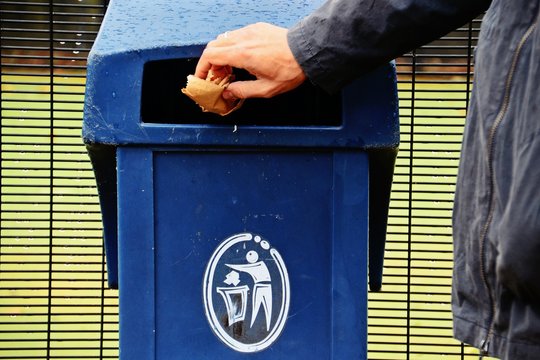 Man dropping garbage into garbage bin