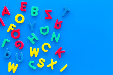 Alphabet for kids concept. English letters in disorder on blue background top view copy space