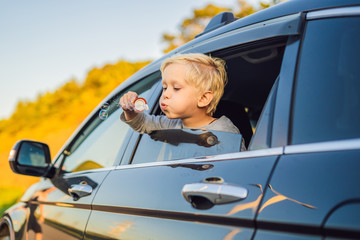 Boy blowing bubbles in the car window. Traveling by car with children