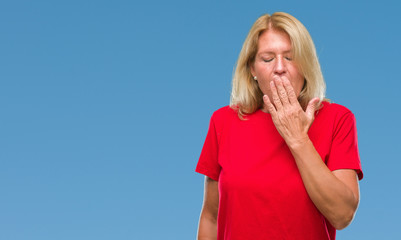 Middle age blonde woman over isolated background bored yawning tired covering mouth with hand....