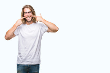 Young handsome man with long hair wearing glasses over isolated background smiling confident showing and pointing with fingers teeth and mouth. Health concept.