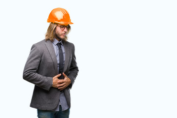 Young handsome architec man with long hair wearing safety helmet over isolated background with hand on stomach because nausea, painful disease feeling unwell. Ache concept.