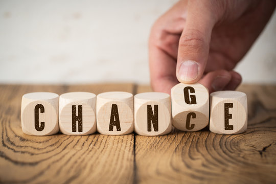 Hand flips one of six cubes with letters, turning the word "change" to "chance" 