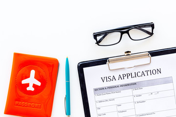 Visa processing, registration. Visa application form near passport cover with airplane on white...