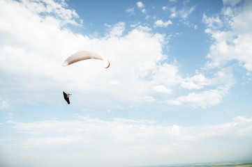 Alone paraglider flying in the blue sky against the background of clouds. Paragliding in the sky on...