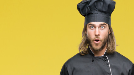 Young handsome cook man with long hair over isolated background afraid and shocked with surprise...