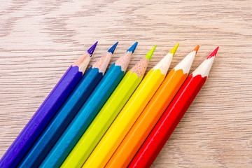 Obraz premium Different colored pencils photo with space for text. Seven pencils of rainbow colors lie on the table. Copyspace. Back to school. Wooden background.