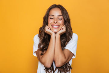 Image of positive young woman 20s with long hair laughing and propping head, isolated over yellow...