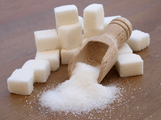 sugar adiction: sugar cubes and wood spoon over wood table