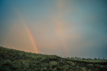 Fototapeta na wymiar Double rainbow in the field, view from the mountain