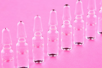 Ampoules with medicine on pink background