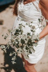 Beautiful young hipster pregnant girl enjoying a sunny beautiful day walking along the beach picking wild plants and looking happy.