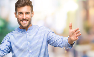 Young handsome man over isolated background looking at the camera smiling with open arms for hug. Cheerful expression embracing happiness.