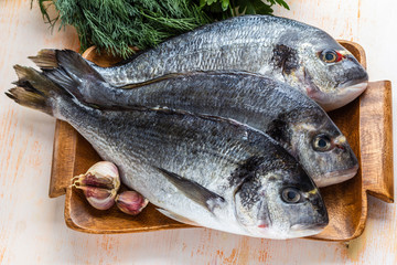 Three are ready to cook raw dorado fish on a wooden tray. Top view